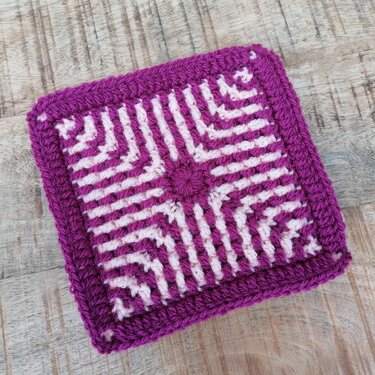 Gehäkeltes Quadrat in Lila und Rosa mit gestreiftem Muster