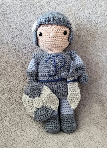 Gehäkelte Amigurumi-Ritterpuppe mit Schild und Schwert in Grautönen