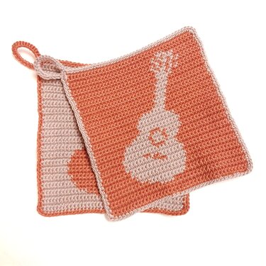 Zwei gehäkelte quadratische Topflappen in Terrakotta und Beige mit Gitarrenmotiv; der obere Topflappen mit Aufhängeschlaufe.