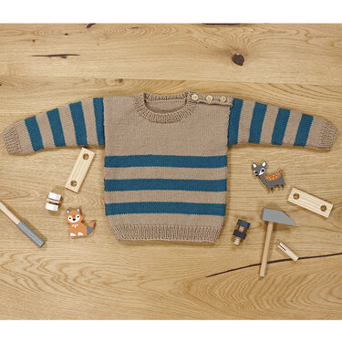 Gestrickter Kinderpullover in Beige mit petrolfarbenen Streifen und Schulterknöpfen auf Holzboden