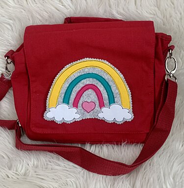 Rote Umhängetasche mit appliziertem Regenbogen, zwei weißen Wolken und kleinem pinken Herz