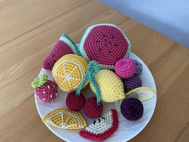 Teller mit gehäkeltem Obst: Wassermelone, Zitrone, Kirschen, Apfelspalt und Beeren