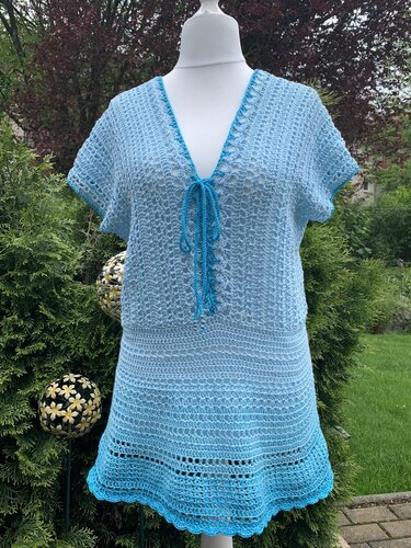 Hellblaue gehäkelte Tunika mit passendem Rock auf einer Schneiderbüste im Garten