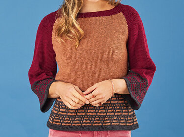 Gestrickter Damenpullover in Braun und Weinrot mit Raglanärmeln und gemustertem Saum, getragen von einem Modell mit gefalteten Händen