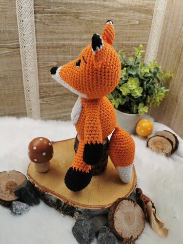 Seitansicht eines gehäkelten orange-weißen Amigurumi-Fuchses mit schwarzer Nase und Pfoten