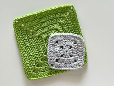 Two crocheted granny squares, large green and small gray, on a white background.