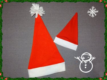 Zwei rote Weihnachtsmützen in verschiedenen Größen, eine mit weißem Bommel, auf grauem Hintergrund