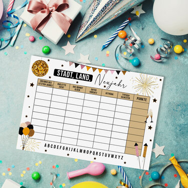 Spielblatt 'Stadt, Land, Neujahr' mit Spalten neben Konfetti, Luftschlangen und Partyhut auf blauem Hintergrund