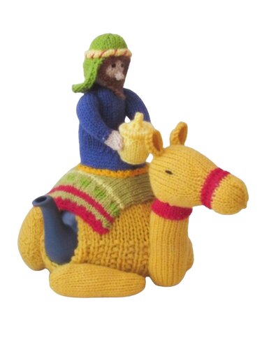 Yellow knitted camel tea cosy with a small rider and visible blue teapot spout and handle