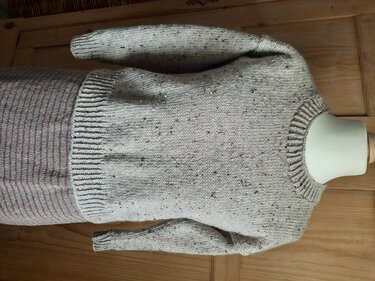 Beiger Strickpullover mit dezenten Sprenkeln und Rippenbündchen auf Schaufensterpuppe
