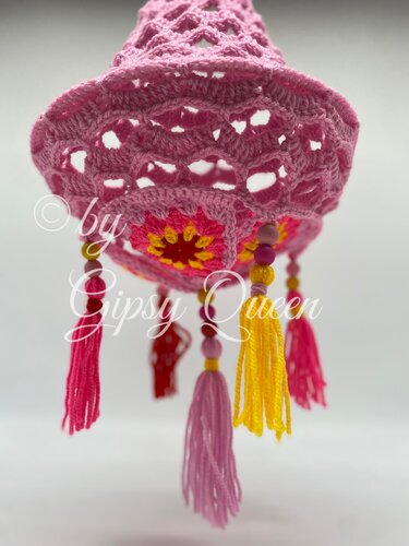 Gehäkelter rosa Deko-Anhänger mit Lochmuster, gelb-pinkem Blütenmotiv, bunten Quasten und Perlen