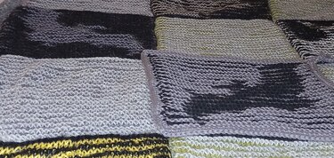 Gestricktes Patchwork mit Quadraten in Grau, Schwarz und Grün und gelb-schwarzem Streifen