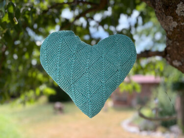 Türkisgrünes gestricktes Herz, an einem Baum hängend