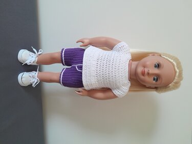 Puppe mit gehäkeltem weißem Top und lila Shorts mit heller Kante