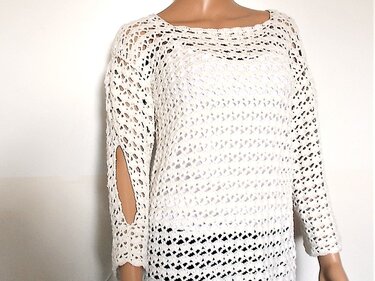Weißer, locker gehäkelter Damenpullover mit langen Ärmeln und seitlichen Schlitzen, auf einem Mannequin präsentiert.