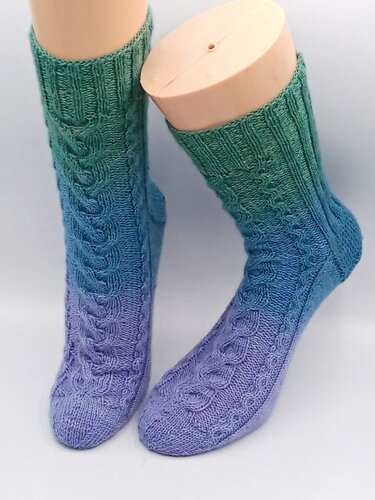 Gestrickte Socken mit grün-blau-violettem Farbverlauf und Zopfmuster