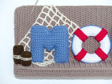 Gehäkelte maritime Wanddekoration mit blauem Buchstaben M und Rettungsring