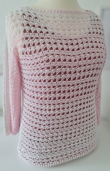 Gehäkelter zartrosa Damenpullover mit Lochmuster auf Schaufensterpuppe