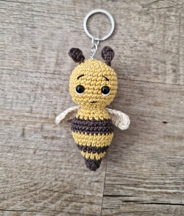 Gehäkelter Bienen-Schlüsselanhänger mit Metallring auf Holz