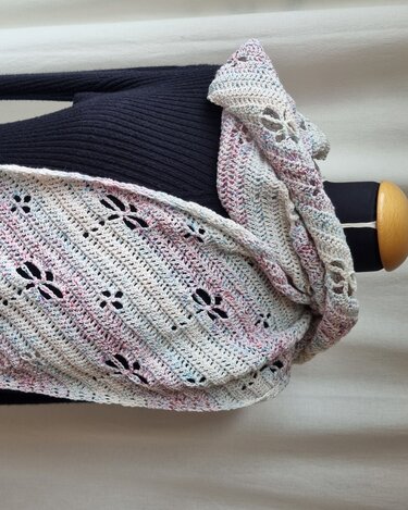 Handgehäkelter Schal in Pastellfarben mit Blumen‑Lochmuster, locker über dunklem Oberteil drapiert