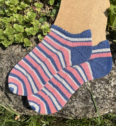 Gestrickte Kurzsocken mit rosa, blauen und weißen Streifen auf einem Sockenblocker