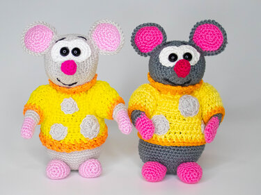 Zwei gehäkelte Amigurumi-Mäuse (hell- und dunkelgrau) mit gelben Pullovern und pinken Details