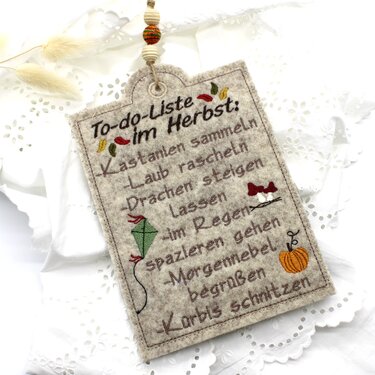 Besticktes Filzschild mit Schrift 'To-do-Liste im Herbst', Drachen-, Kürbis- und Blattmotiven sowie Ösenaufhängung