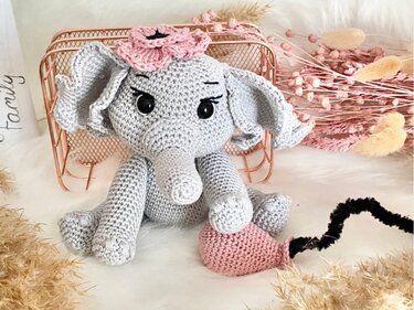 Häkel-Elefant aus grauem Garn mit rosa Blume und rosafarbenem Häkel-Accessoire