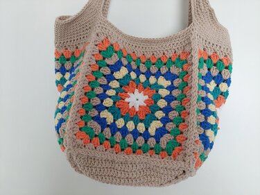 Gehäkelte Henkeltasche aus Granny Squares in Beige, Orange, Blau, Grün, Gelb und Weiß.