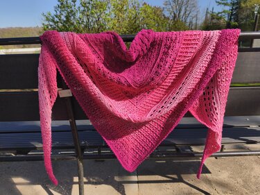Gehäkeltes Dreieckstuch in Pink mit Farbverlauf auf einer Bank