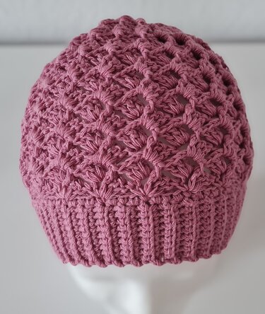 Rosafarbene gehäkelte Mütze mit Lochmuster und geripptem Bündchen auf Kopfmodell