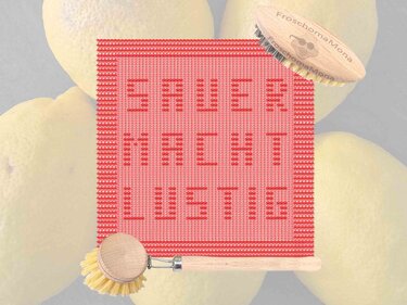 Quadratisches korallenrotes gestricktes Küchentuch mit eingestricktem Text, auf Zitronen und neben Holz-Küchenbürsten