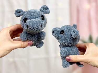Zwei blaue gehäkelte Nilpferd-Amigurumis, von Händen gehalten