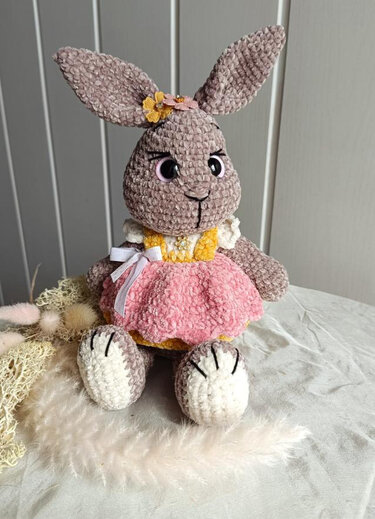 Amigurumi-Häschen mit langen Ohren trägt ein Kleid mit flauschigem rosa Rock und Schleife