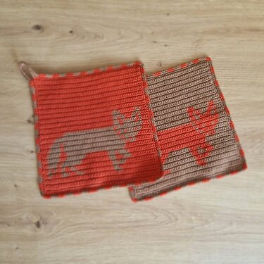 Zwei gehäkelte rechteckige Topflappen in Orange und Beige mit Tier-Motiv
