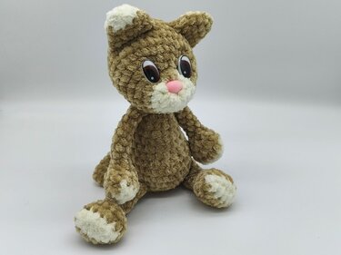 Detailansicht sitzende gehäkelte Amigurumi-Katze in Braun mit weißen Pfoten und rosa Nase