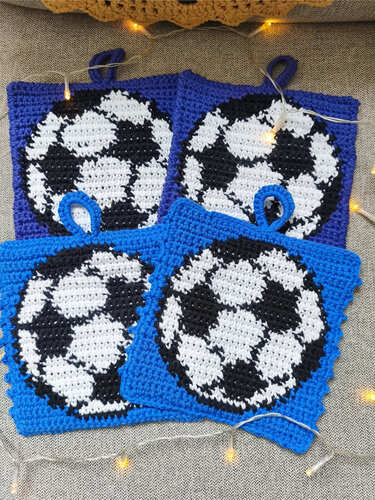 Four blue crocheted square potholders with black-and-white soccer ball motifs and hanging loops