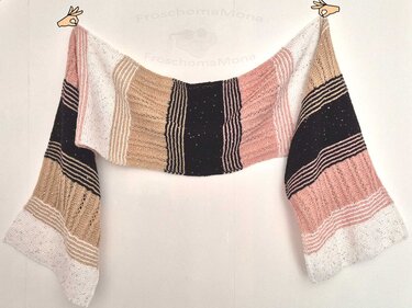 Gestrickter Schal mit horizontalen Streifen in Schwarz, Rosa, Beige und Weiß, teilweise mit Pailletten, an weißer Wand
