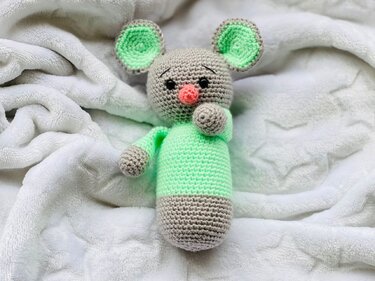 Gehäkelte Amigurumi-Maus in Grau und Mintgrün auf weißer Decke