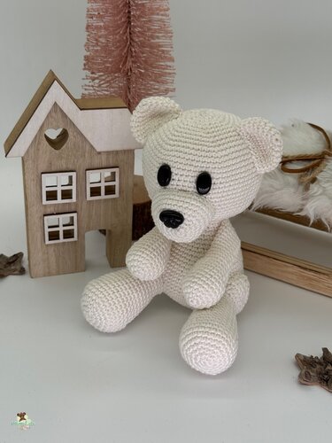 Cremefarbener gehäkelter Amigurumi-Teddybär sitzend mit dunklen Augen