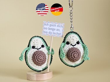 Zwei gehäkelte Avocado-Hälften, ein Schlüsselanhänger und eine Dekofigur mit Schild.