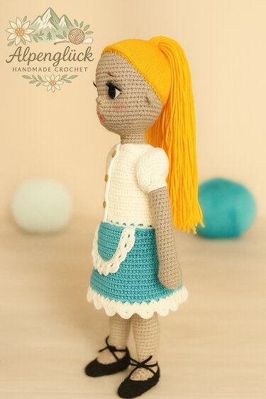 Seitenansicht einer gehäkelten Amigurumi-Puppe mit gelbem Zopf und türkis-weißem Kleid