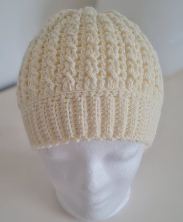 Cremefarbene gehäkelte Damenmütze auf Kopfmodell mit Rippenbündchen und strukturierter Maschenstreifen