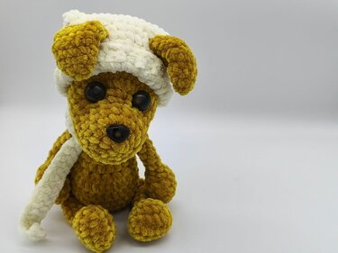 Gehäkelter senfgelber Amigurumi-Hund mit weißer Mütze und Schal