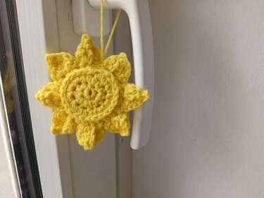 Gehäkelter gelber Sonnenanhänger an weißem Fenstergriff