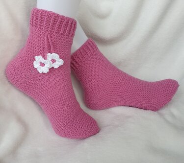Pink gehäkelte Socken mit weißen Blüten auf weißem Untergrund