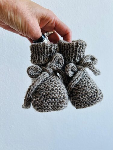Gestrickte Babyschuhe in Grau, kraus rechts gearbeitet mit geripptem Bündchen und Bindeband