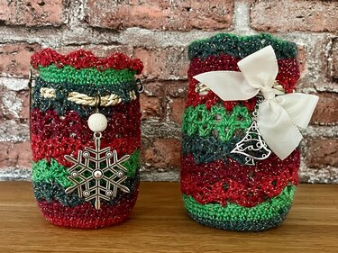 Zwei gehäkelte Hüllen für Windlichter in Rot-Grün mit Schleife und Schneeflocken-Anhänger