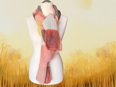 Mehrfarbiger Strickschal mit Farbfeldern in Rosa, Orange, Gelb und Grau, drapiert an einer weißen Schaufensterpuppe.