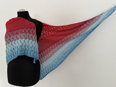 Gestricktes Dreieckstuch mit Rot‑zu‑Hellblau‑Farbverlauf und Lochmuster auf schwarzer Schneiderpuppe